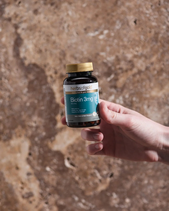Herbs of Gold Biotin 3mg bottle held outdoors